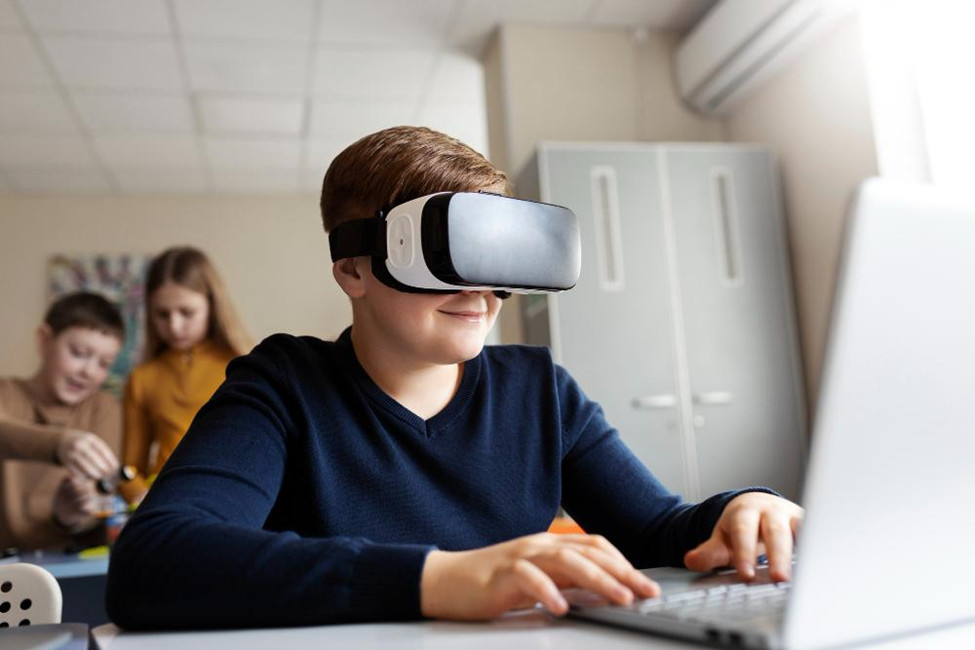 A young boy using a laptop and VR glasses